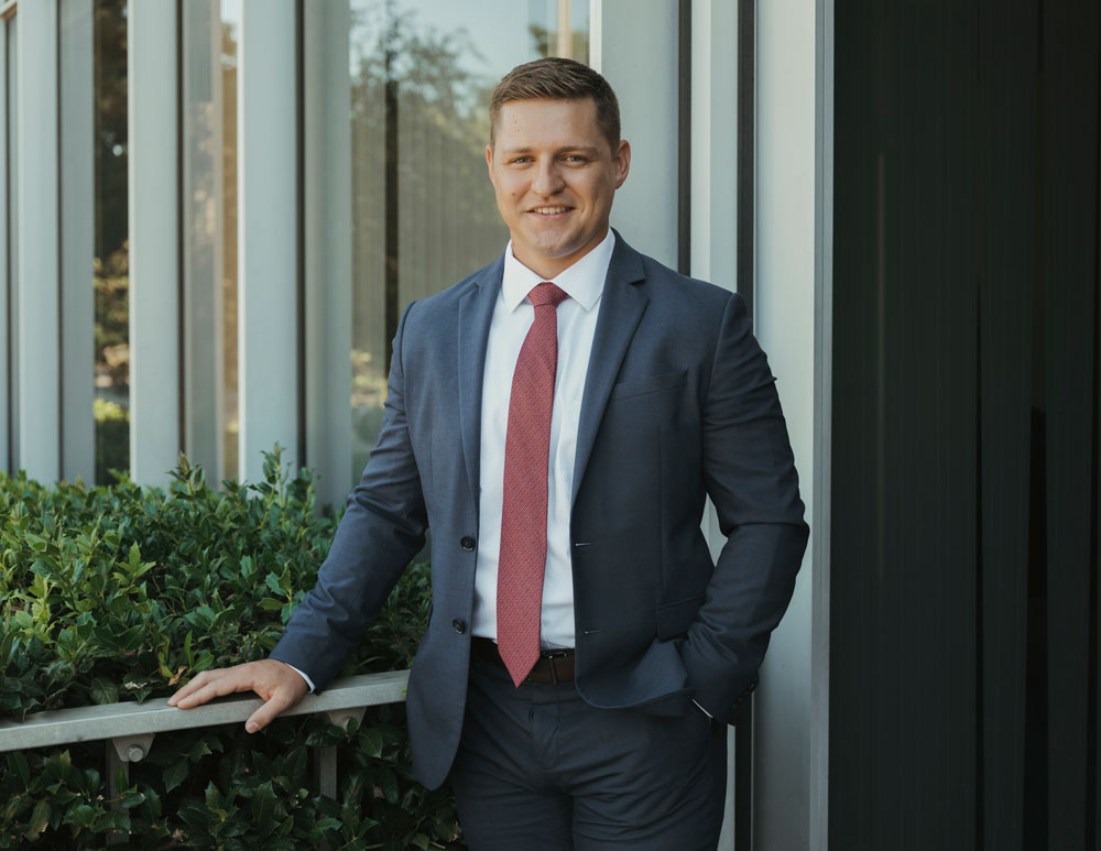Shade Kremer, founder of Kremer Law, in professional attire, standing confidently beside greenery and a modern building, representing personal injury advocacy in Oklahoma City.