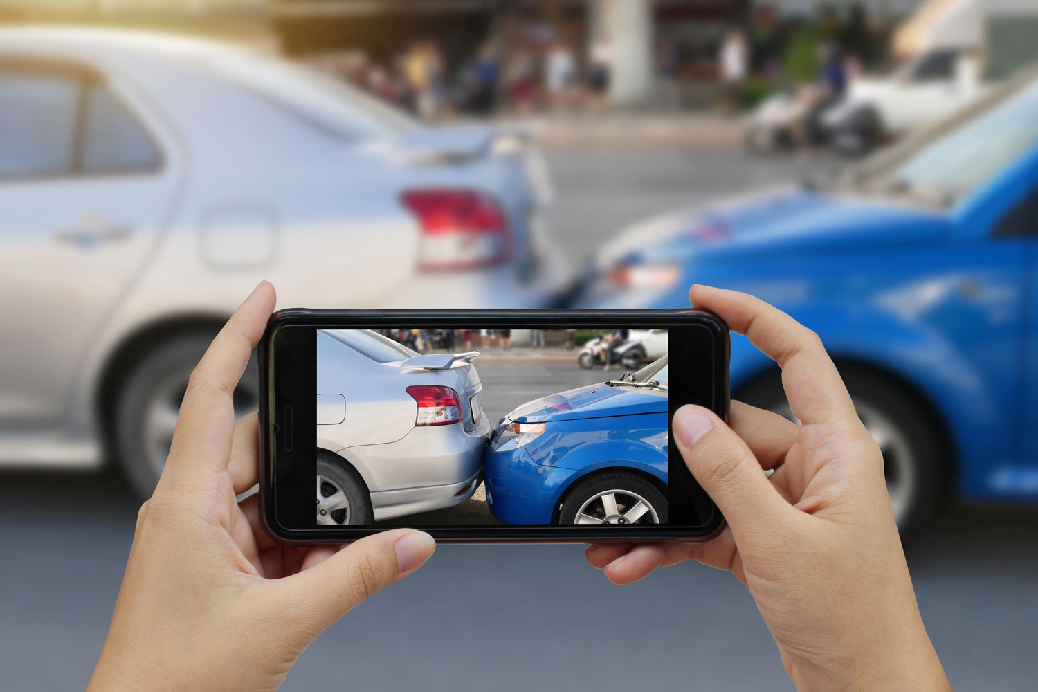 Image of a smart phone taking a picture of a car accident.