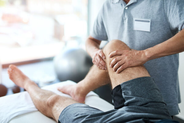 Man's injured knee being treated by a physical therapist.