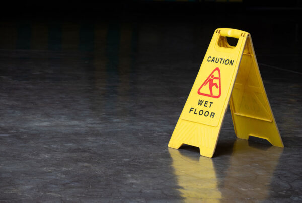 "Caution: Wet Floor" sign on a dark floor.