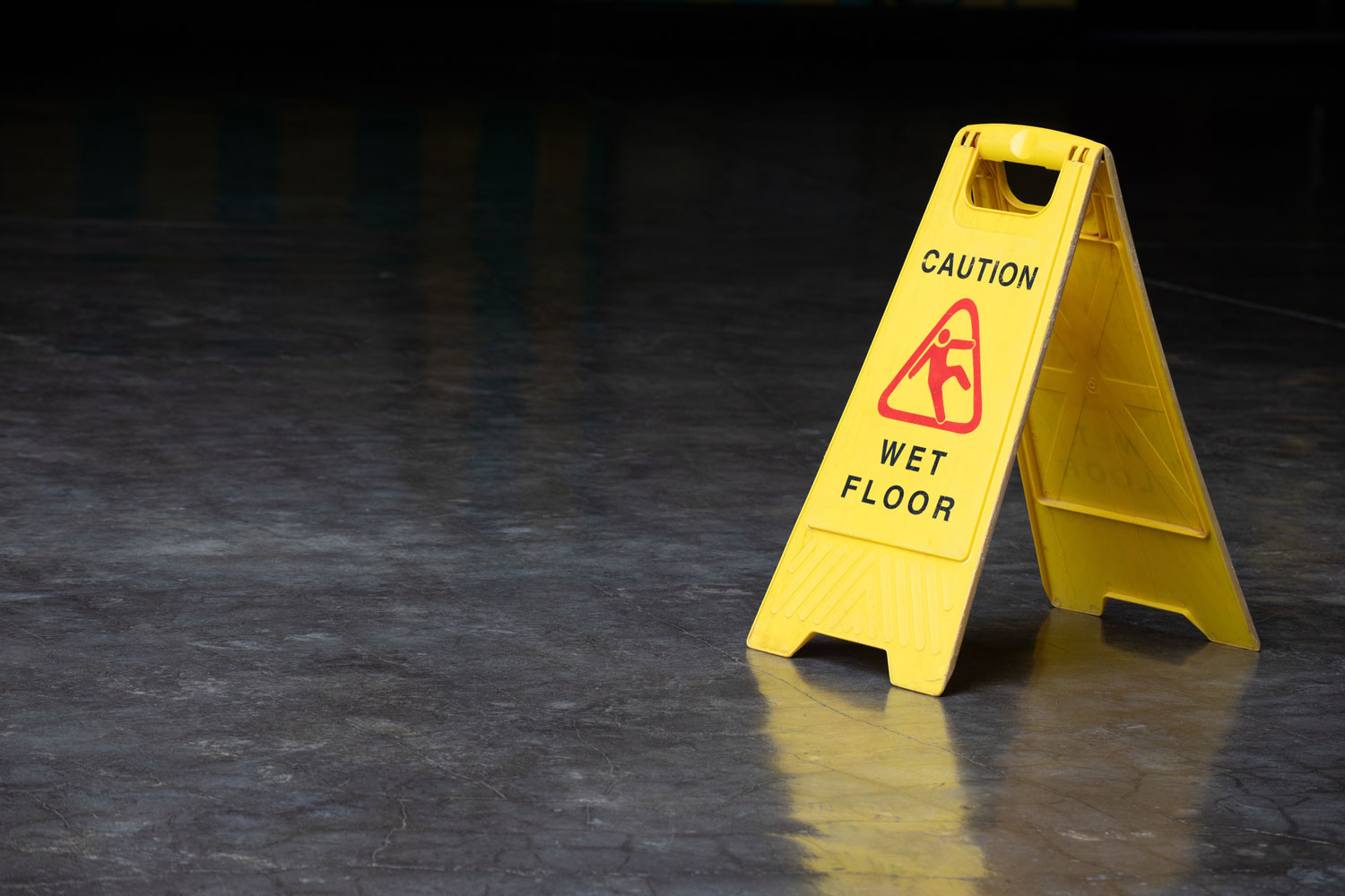 "Caution: Wet Floor" sign on a dark floor.